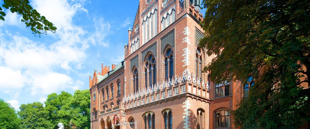 A historic building with intricate architecture, large arched windows, and a prominent clock tower.