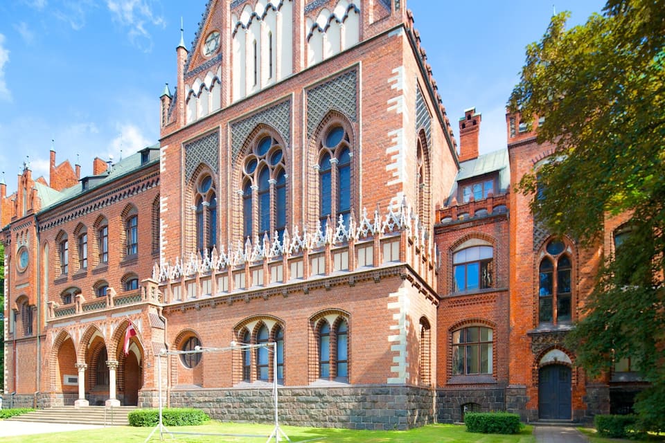 Ein großes, historisches Backsteingebäude mit Rundbogenfenstern und einem Glockenturm.