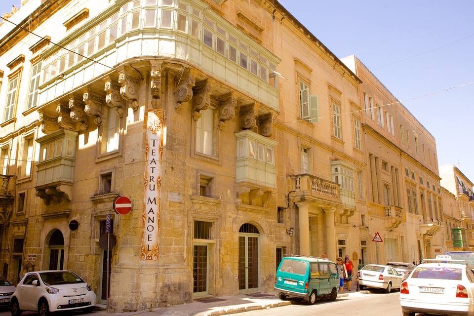 Un edifici històric amb arquitectura ornamentada i un cartell que diu "TEATRU MAN".
