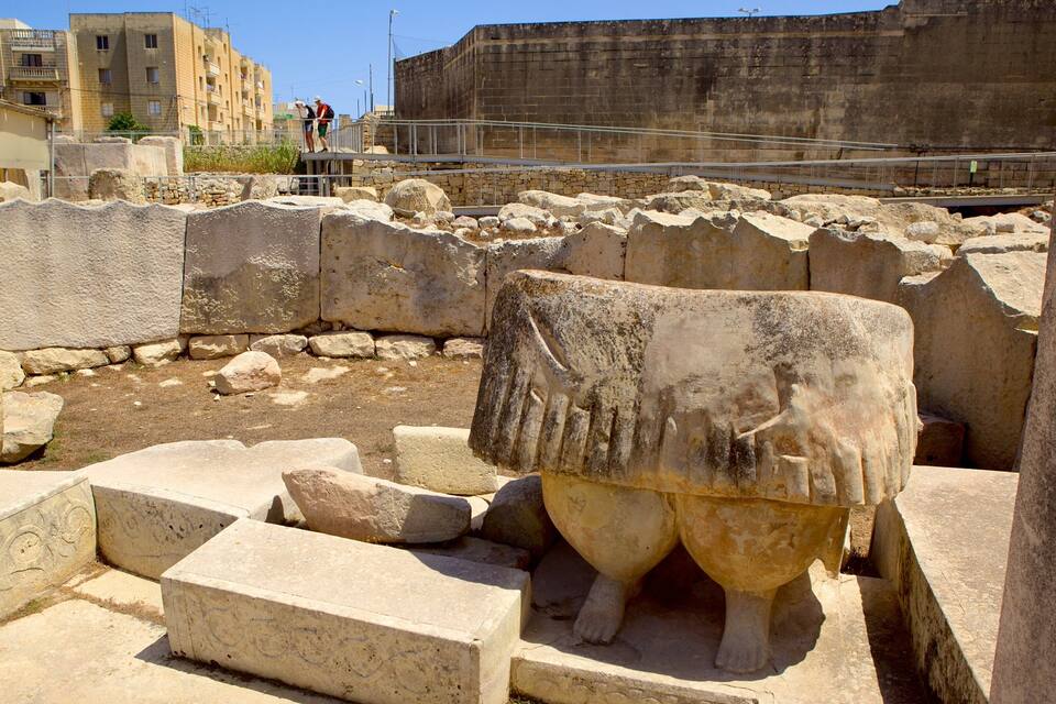 Ruinas antiguas con bloques de piedra y una gran escultura de cabeza de toro.