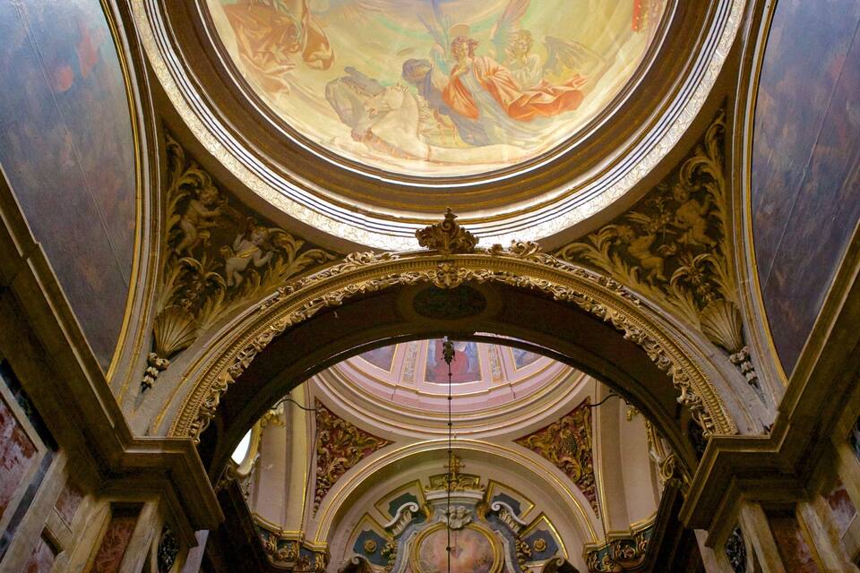 Un sostre ornamentat amb un fresc circular central, detalls d'or elaborats i una clau penjada en forma de cúpula.
