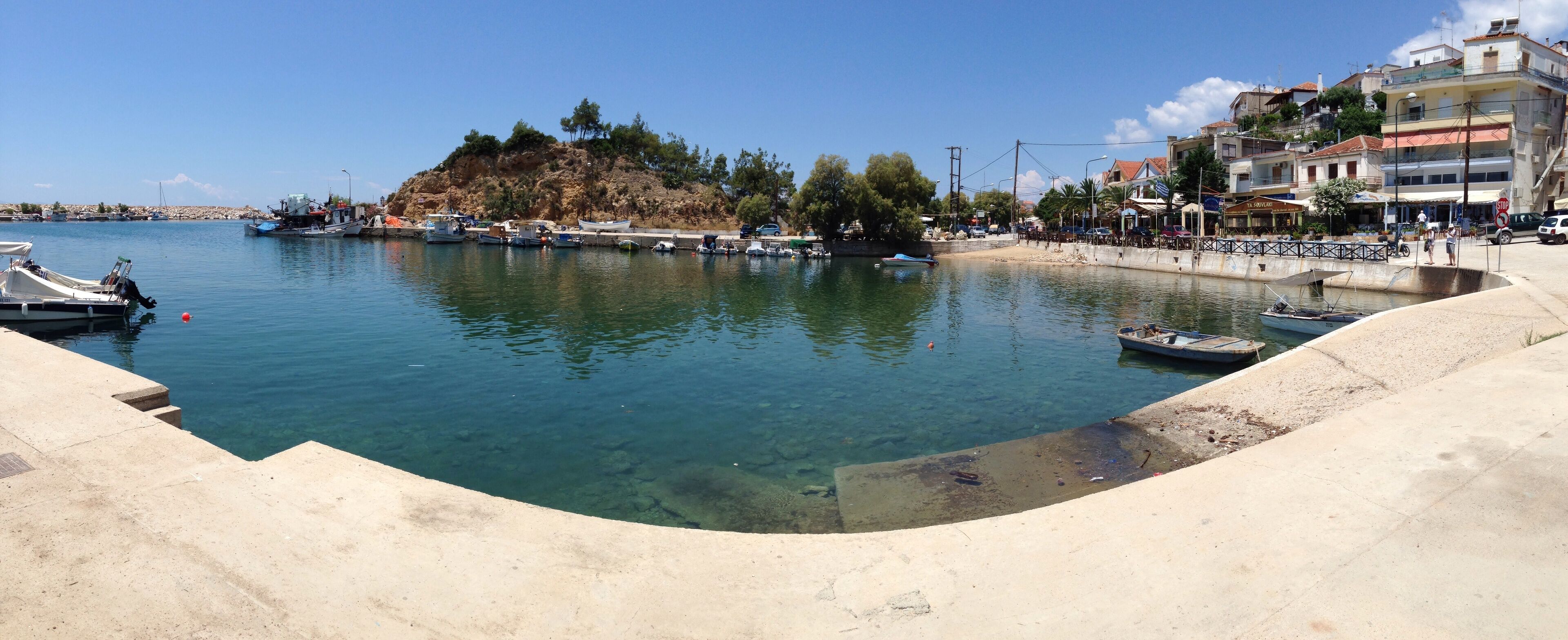A marina with boats docked, a sandy beach, and buildings along the waterfront.