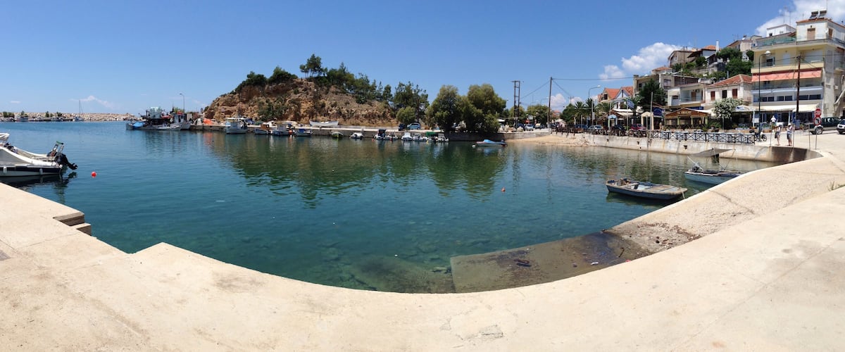 A marina with boats docked, a sandy beach, and buildings along the waterfront.
