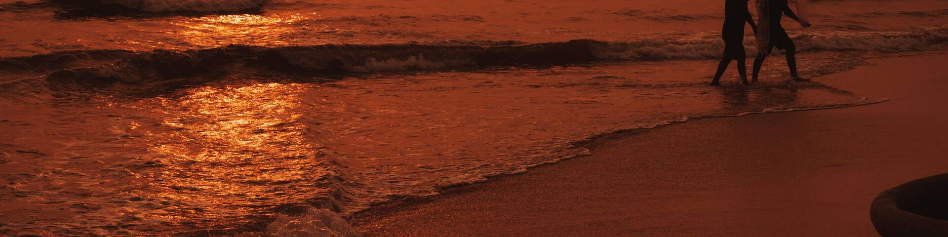 Silhouettes of Vietnamese fishermen on the beach by sea with fishing boats in a fishing village in morning at sunrise in Vietnam
