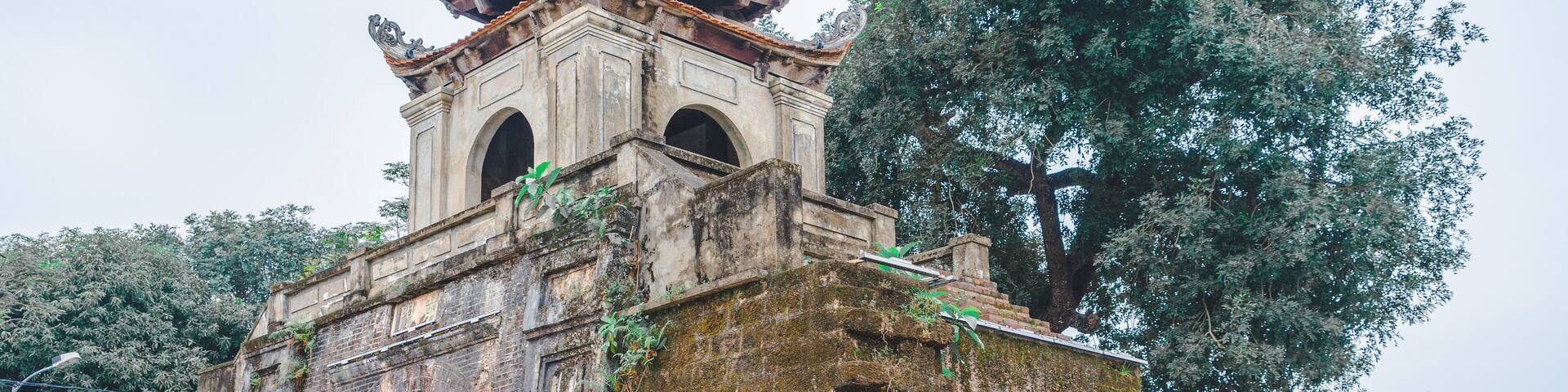 An ancient temple with a traditional roof, a large arched entrance, and a surrounding fence.