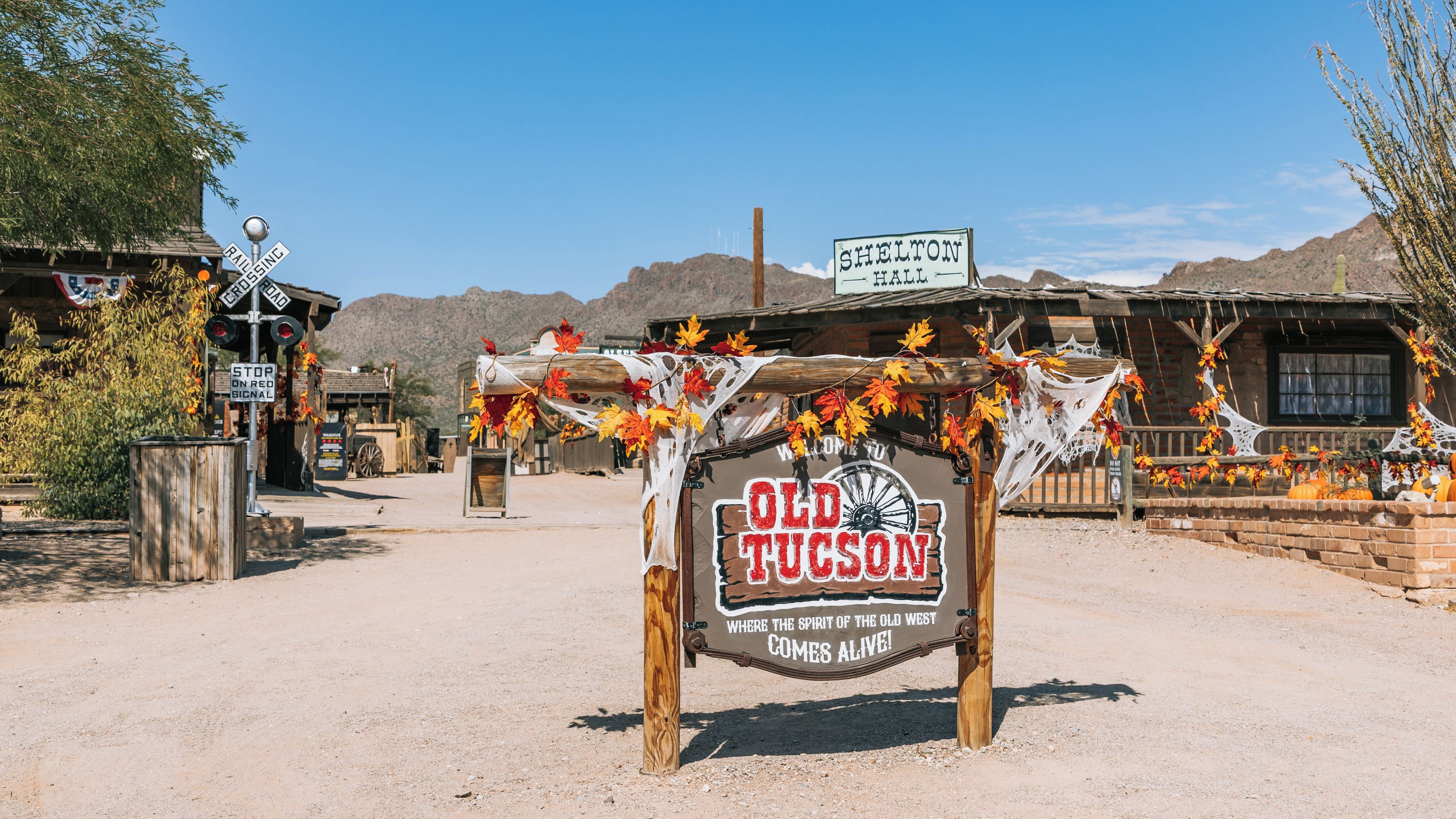 A rustic sign with 'Old Tucson' and a Western theme, surrounded by desert scenery and wooden buildings.