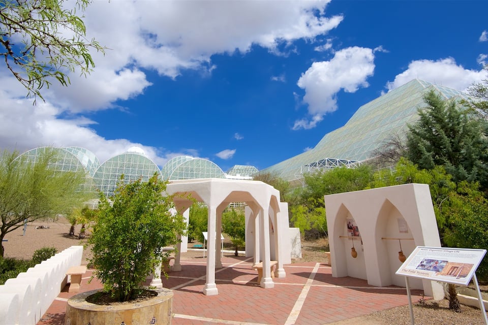 A botanical garden with glass greenhouses, white structures, and a clear blue sky.