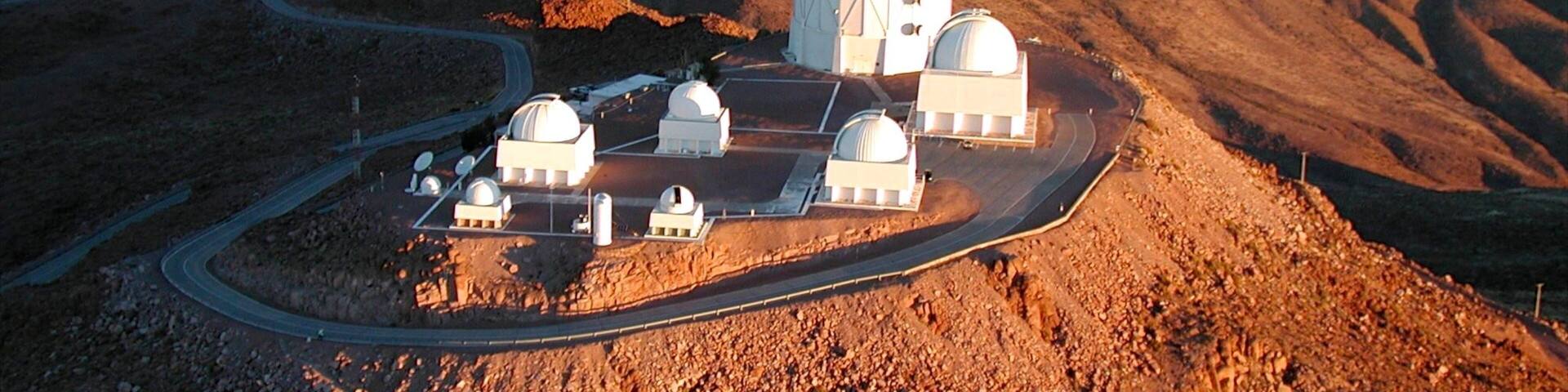 A mountainous landscape with a large observatory featuring multiple domes.