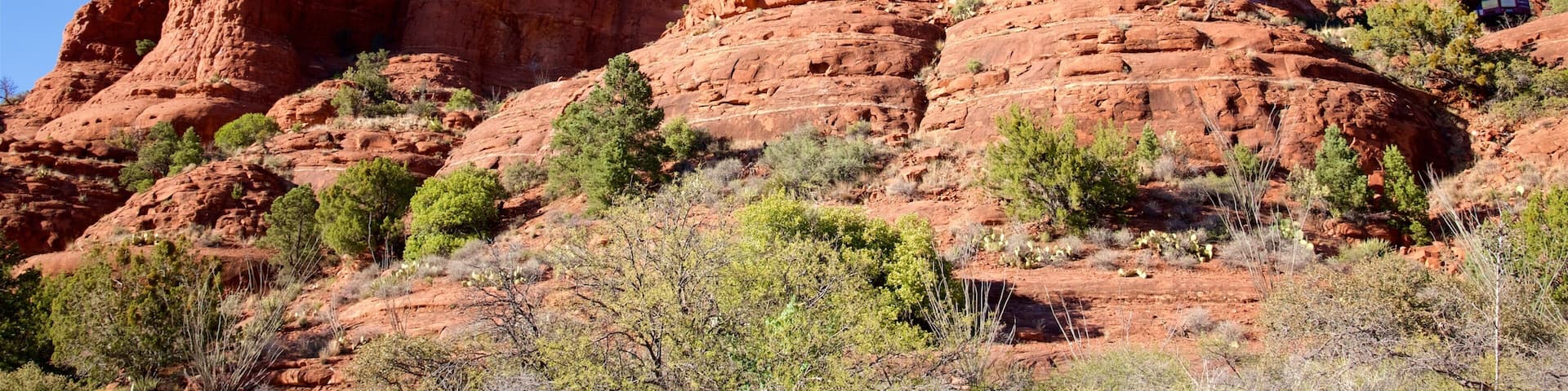 A red rock formation with a cross on top and a building with large windows.