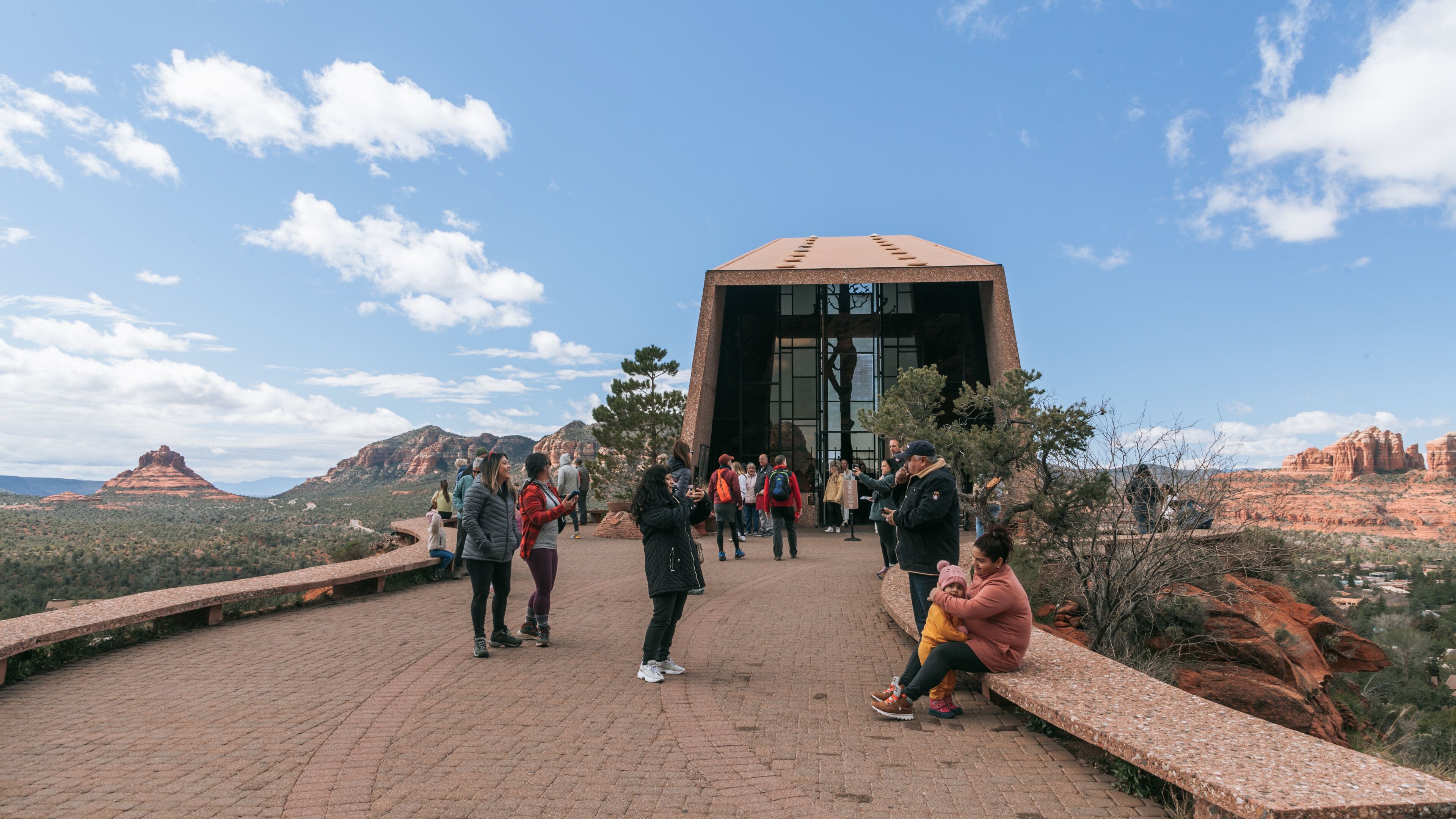 Chapel of the Holy Cross featuring a gorge or canyon and desert views as well as a small group of people