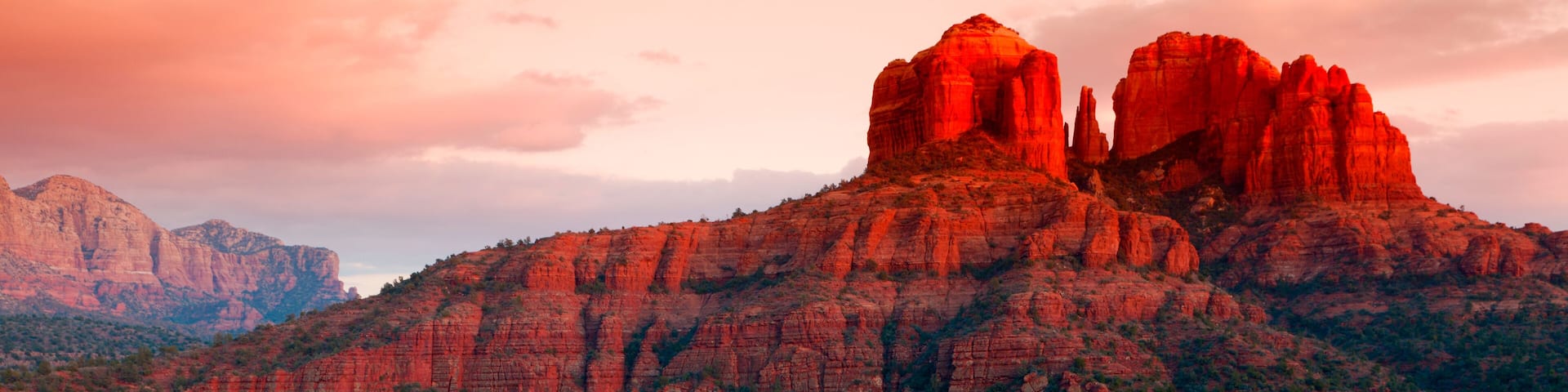 A red rock landscape with a reflective water body and distant mountains.