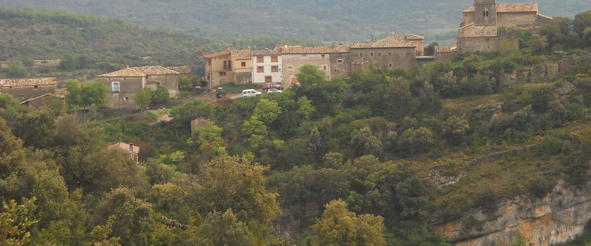 A village with stone buildings and a church on a hillside.