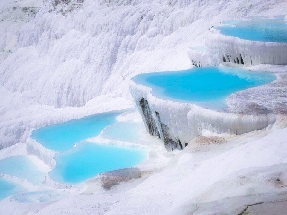 Terraced pools of turquoise water surrounded by white mineral deposits.