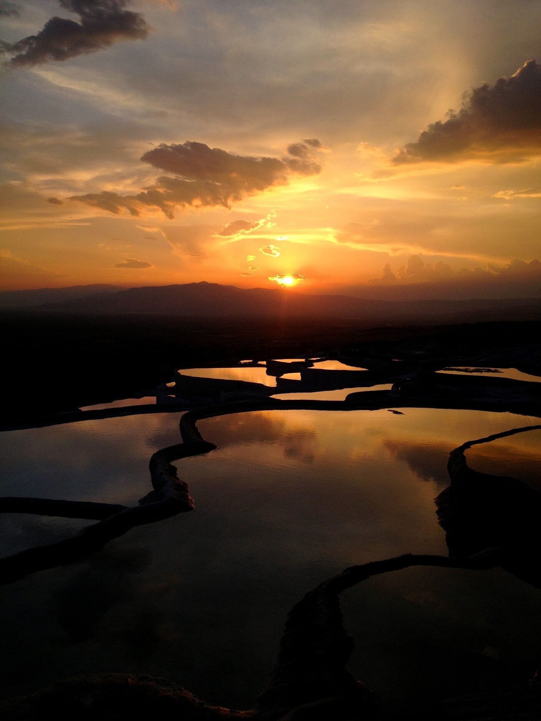 A sunset over a calm body of water with reflections of the sky.