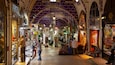 A bustling market with colorful stalls and a patterned ceiling.