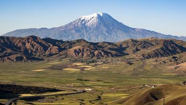 A snow-capped mountain, a valley with fields, and a small town.