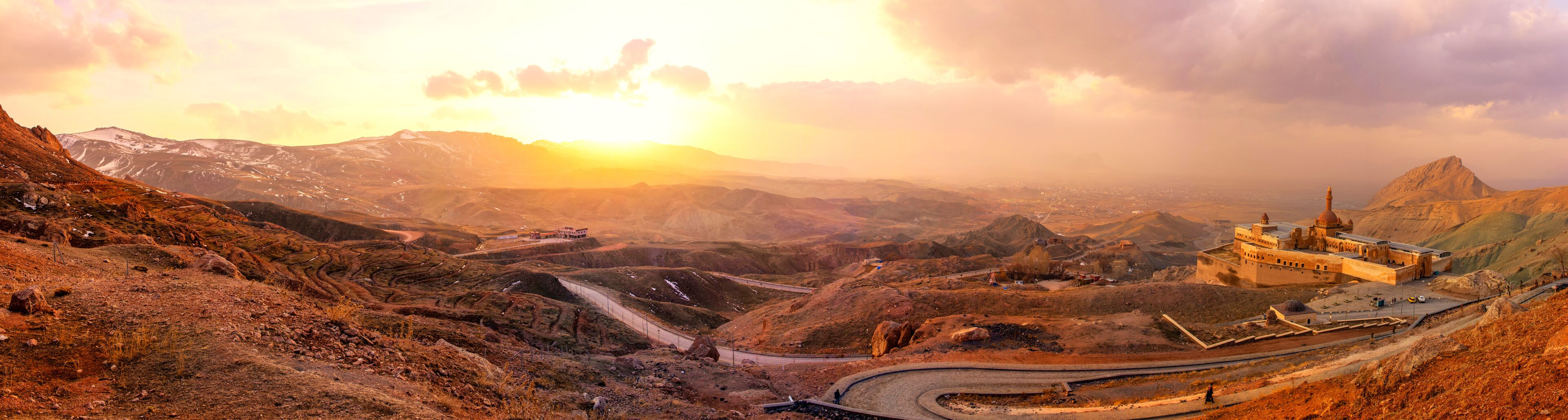 Mountainous landscape at sunrise with winding road and ancient settlement. A breathtaking panoramic rugged mountain range at sunrise. Ishak Pasha Palace Panoramic Doğubeyazit Agri eastern Turkiye