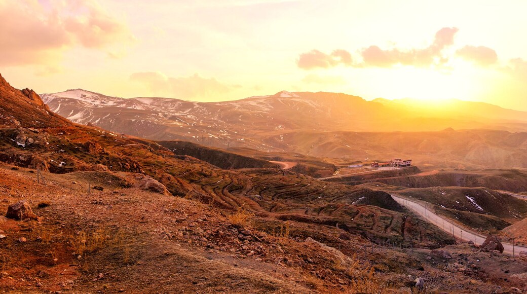 Mountainous landscape at sunrise with winding road and ancient settlement. A breathtaking panoramic rugged mountain range at sunrise. Ishak Pasha Palace Panoramic Doğubeyazit Agri eastern Turkiye