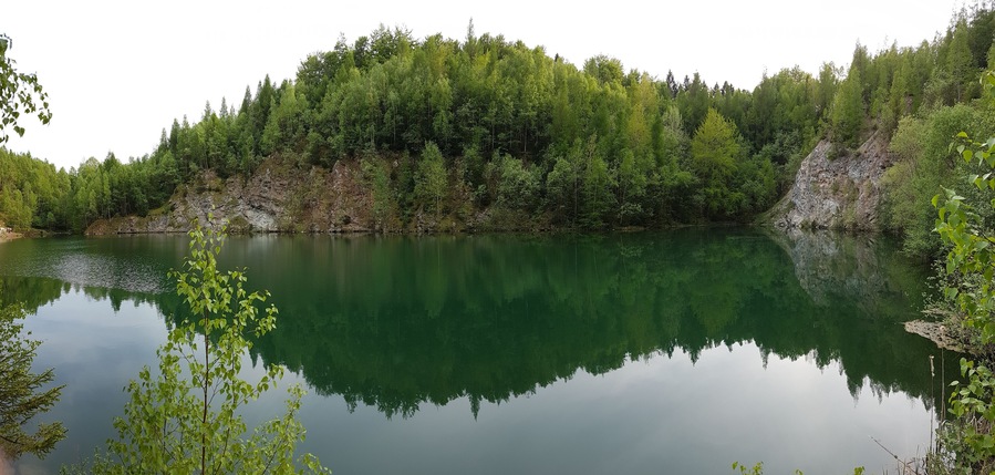 Un lac paisible, entouré d’une forêt dense et de falaises rocheuses.