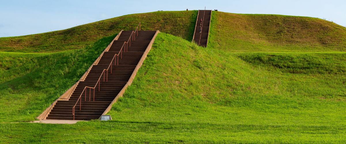 A grassy hill with a set of stairs leading up to a higher point.