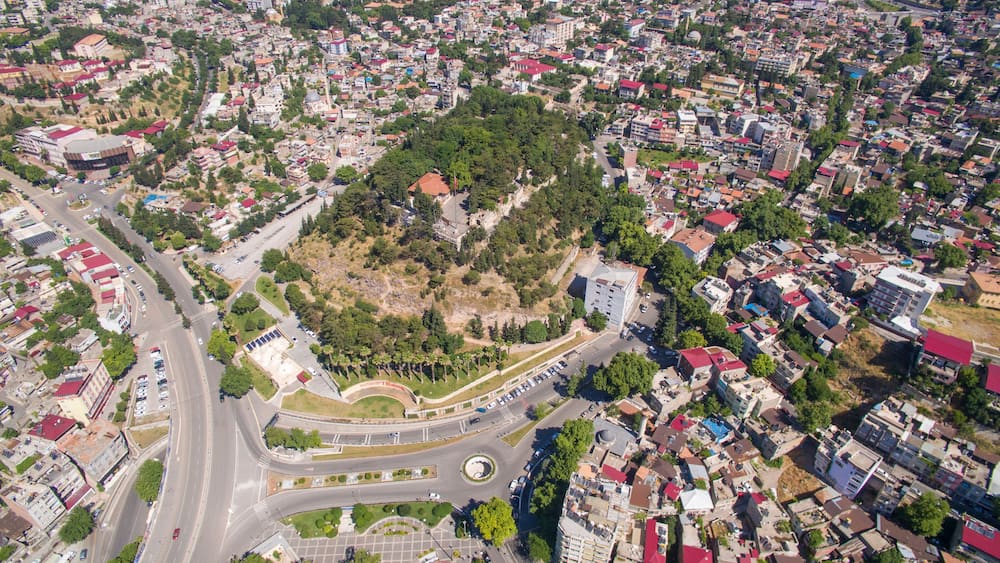 Une vue aérienne d’une ville avec un parc central entouré d’immeubles résidentiels et d’un rond-point.