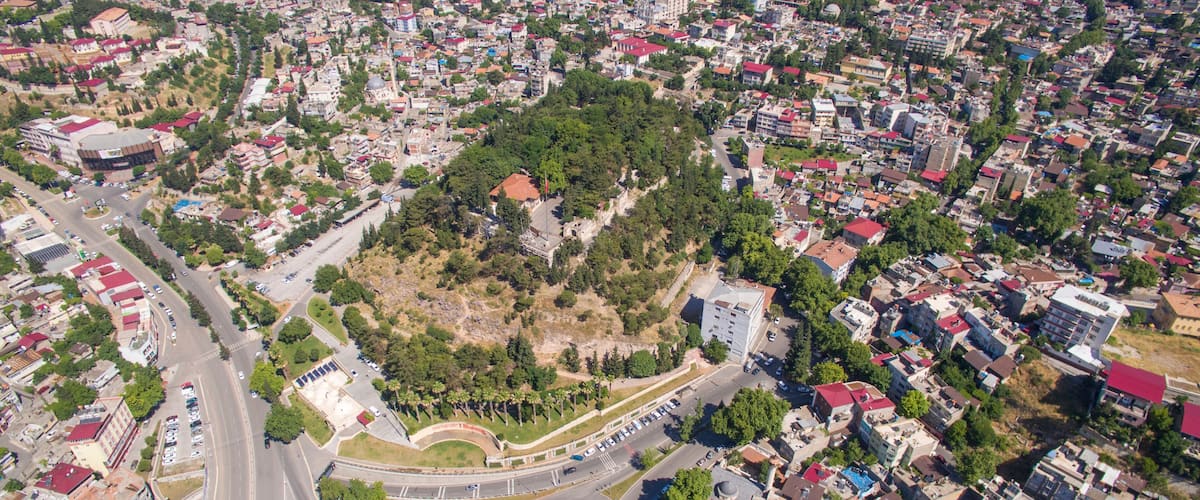 An aerial view of a city with a central park surrounded by residential buildings and a roundabout.