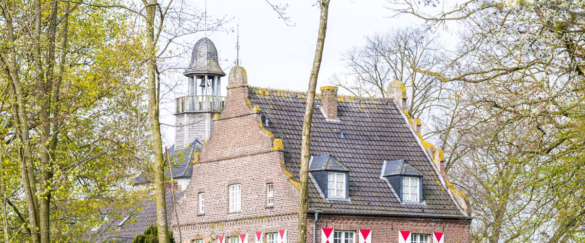 A historic brick building with a bell tower and red and white flags.