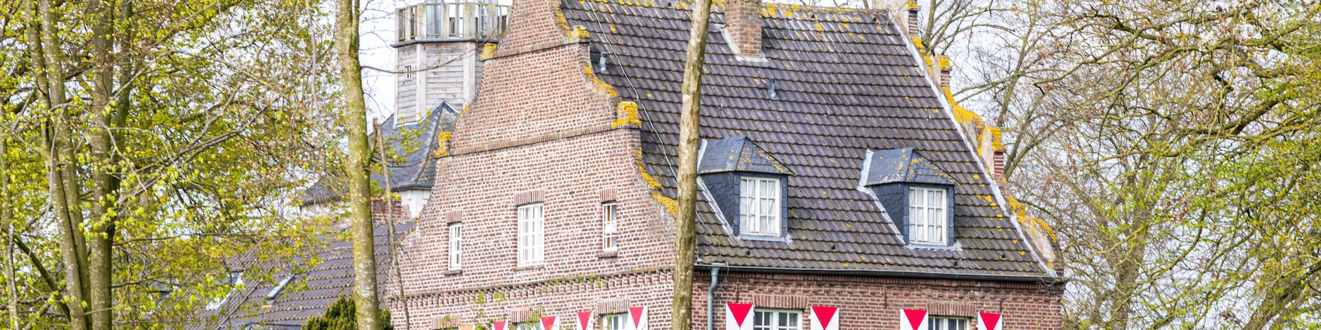 A historic brick building with a bell tower and red and white flags.