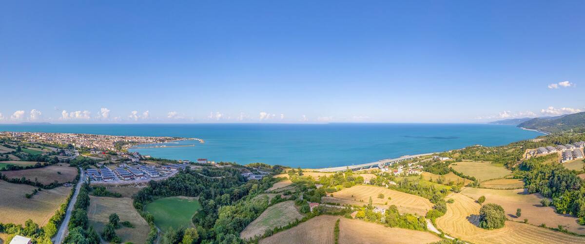 A coastal landscape with fields, a road, and a distant city by the sea.