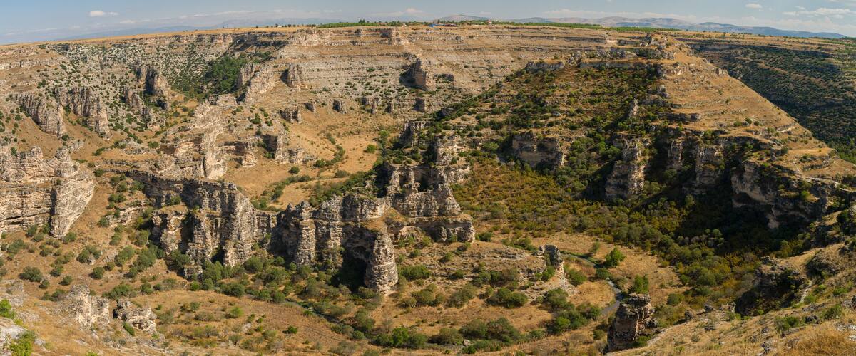 A rugged canyon landscape with rocky formations and sparse vegetation.