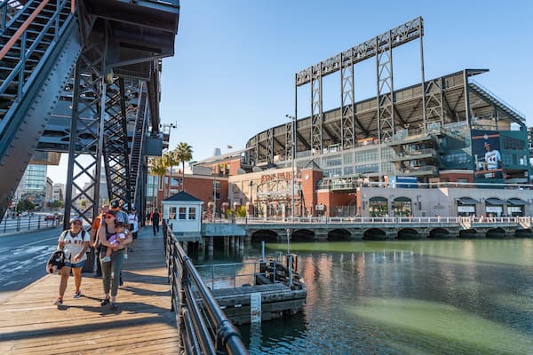 Oracle Park featuring a bay or harbor and street scenes as well as a small group of people