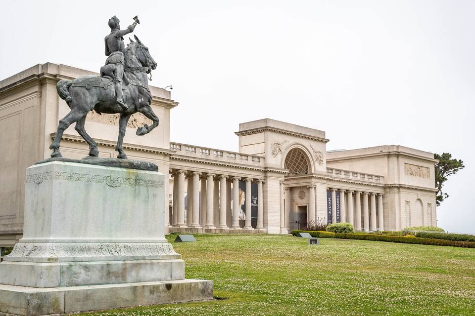 A statue of a man on horseback in front of a large neoclassical building.
