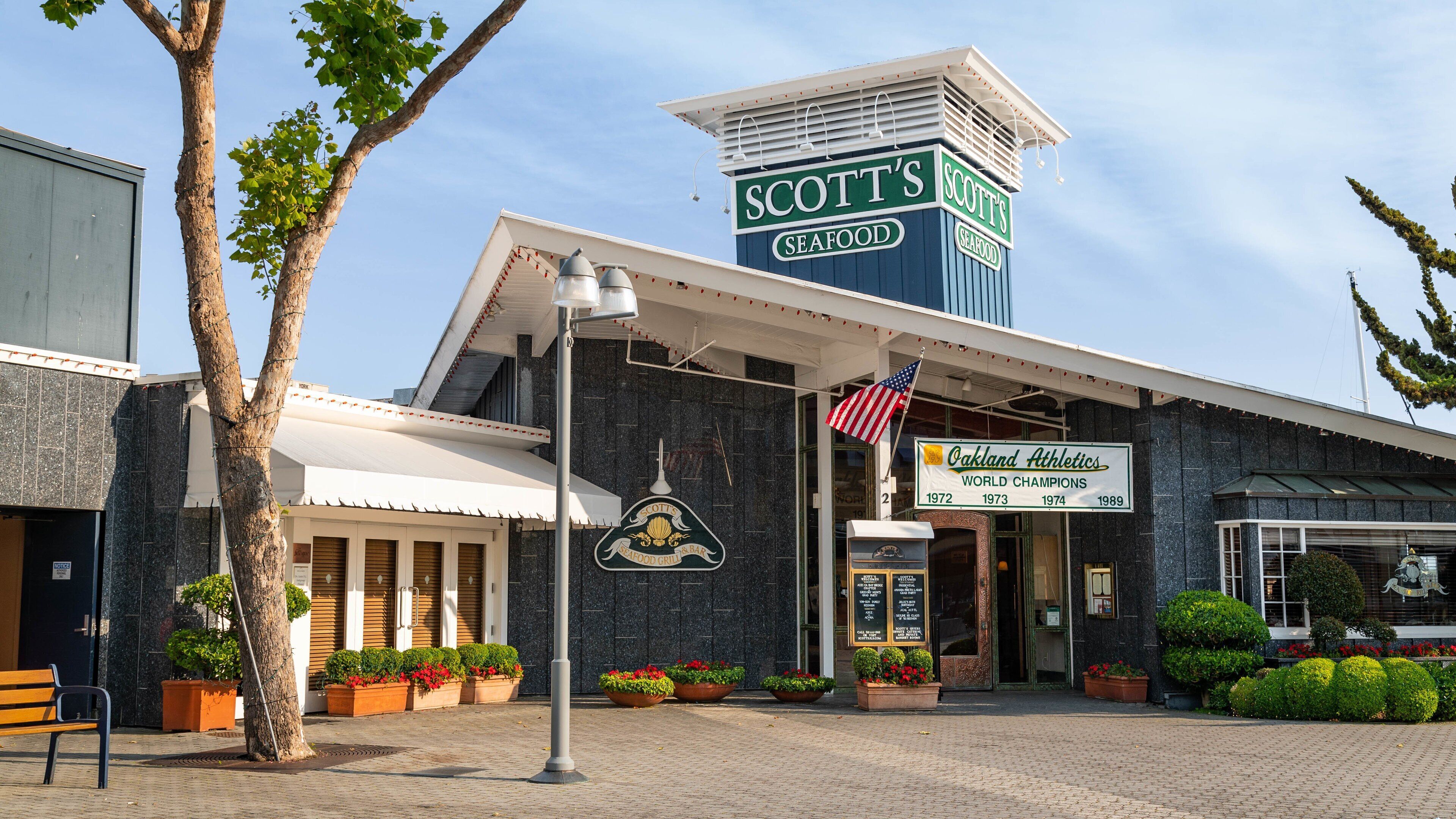 A seafood restaurant with a sign reading "Scott's Seafood Grill & Bar" and an "Oakland Athletics" banner.