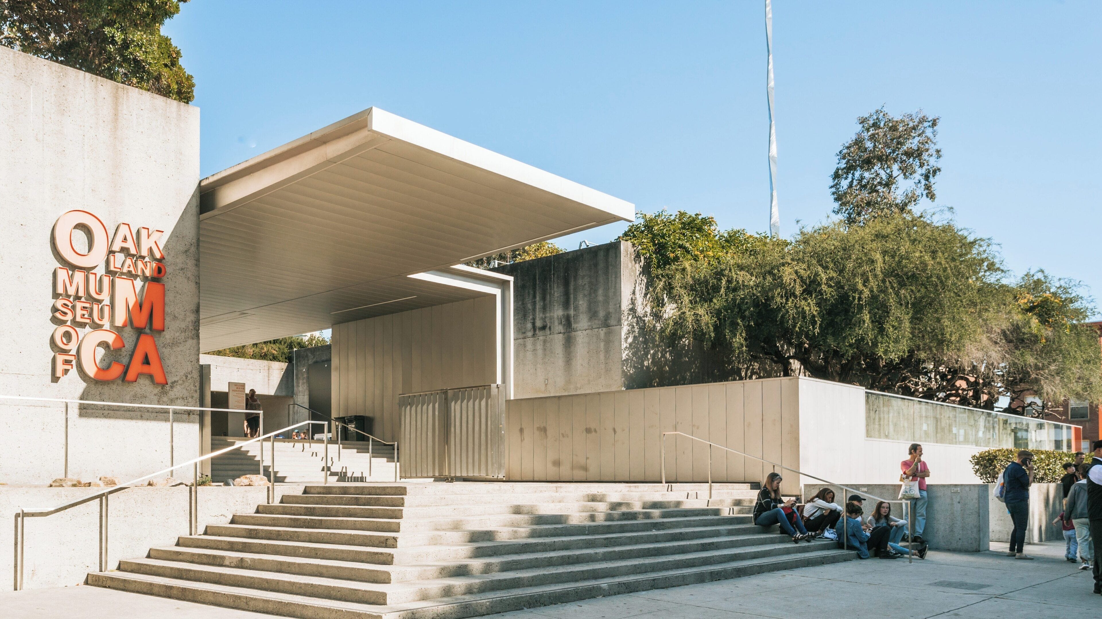 Visitors gather at Oakland Museum of California entrance in Chinatown, Oakland during a sunny day, enjoying the vibrant culture and art exhibitions available