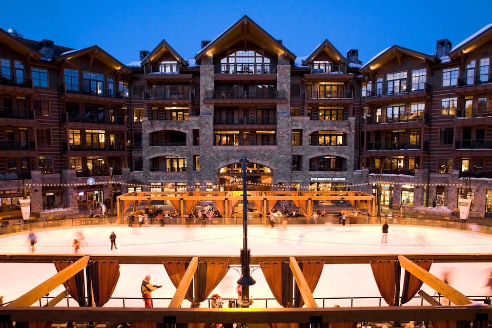Een meerhoog gebouw met een skihut op de achtergrond.