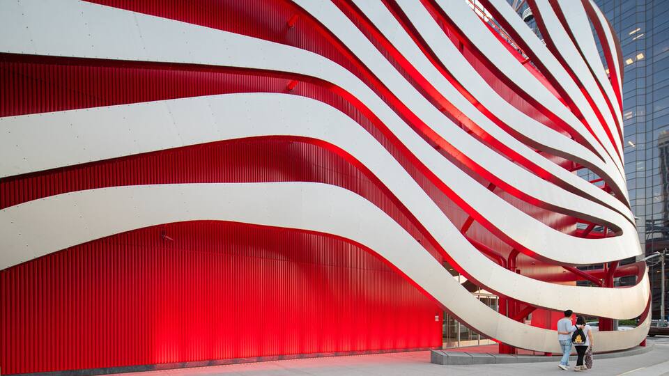 Ein modernes Gebäude mit roter Fassade und weißen, geschwungenen architektonischen Elementen.