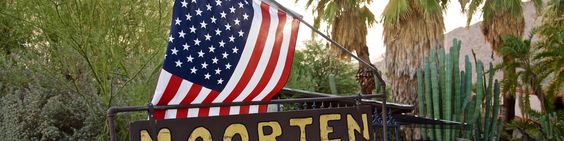 A sign for the Mooren Botanical Garden with an American flag.