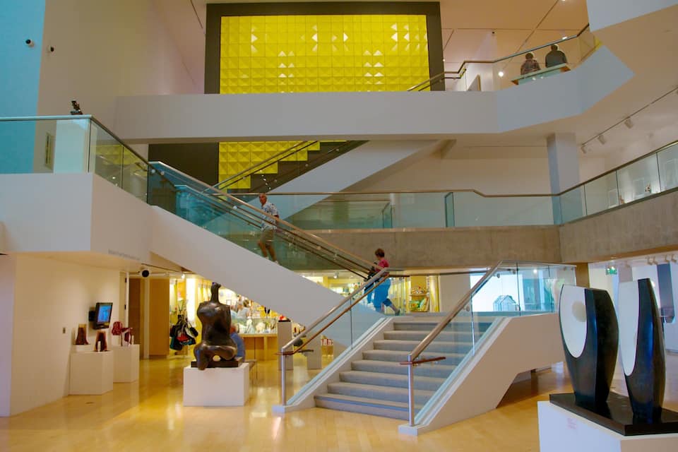 Spazio interno moderno con diversi livelli, ringhiere in vetro e installazioni artistiche contemporanee.