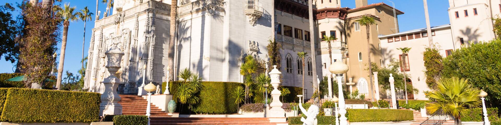 Hearst Castle, San Simeon, California - USA: Close-up view of Hearst Castle from the side. Towers, palm trees, sun, clear blue sky