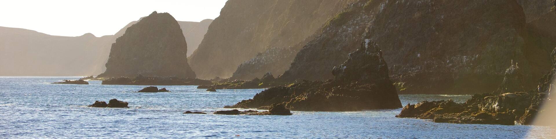 A coastal landscape with rocky cliffs and calm sea.