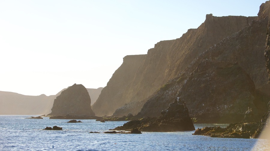 A coastal landscape with rocky cliffs and calm sea.