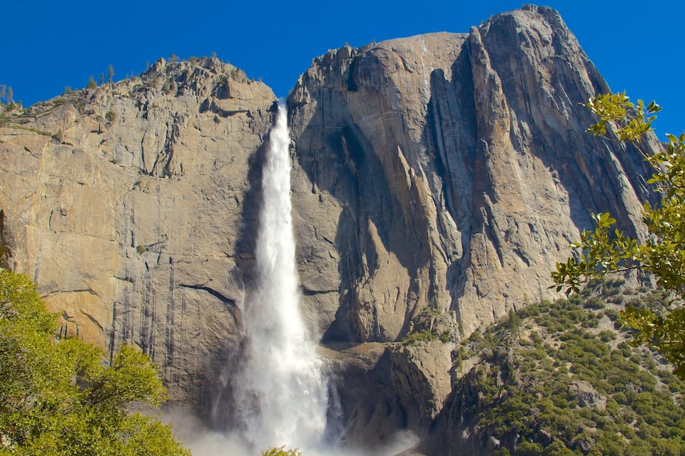 A waterfall cascading down a rocky cliff with a clear blue sky above.