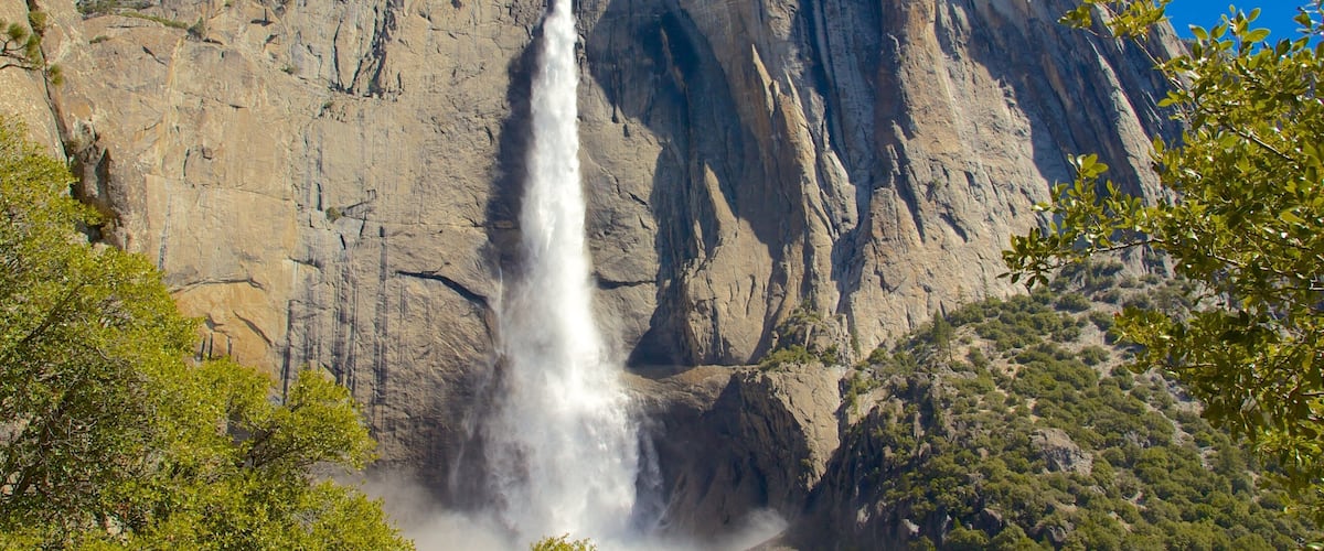 A waterfall cascading down a rocky cliff with a clear blue sky above.
