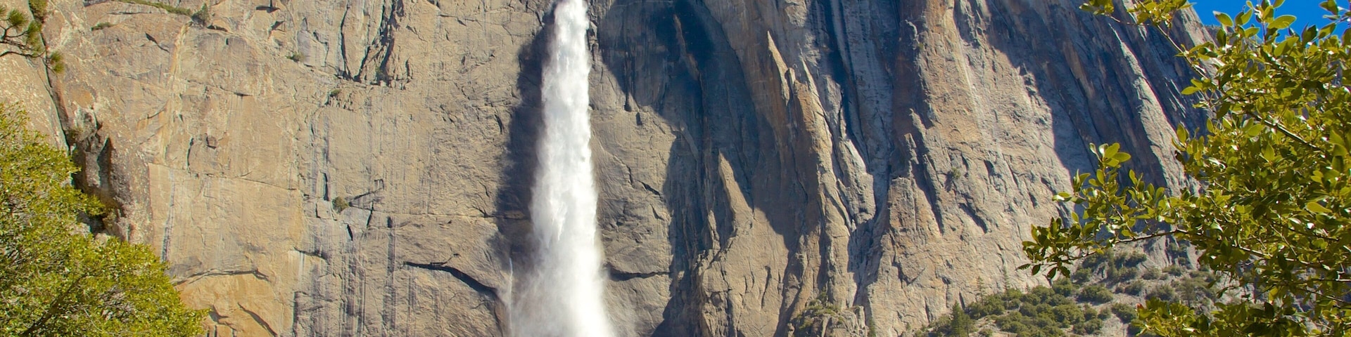 A waterfall cascading down a rocky cliff with a clear blue sky above.