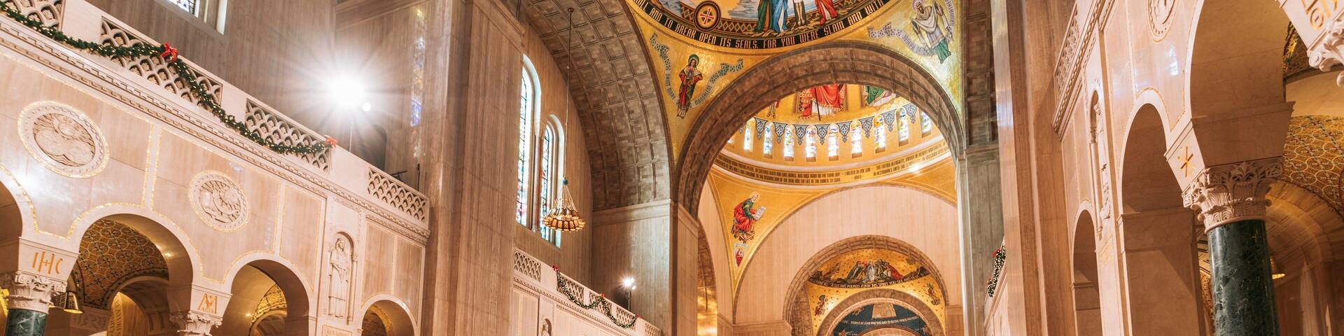 Interior de una iglesia con techos altos de arcos, bancos de madera y detalladas decoraciones en las paredes.