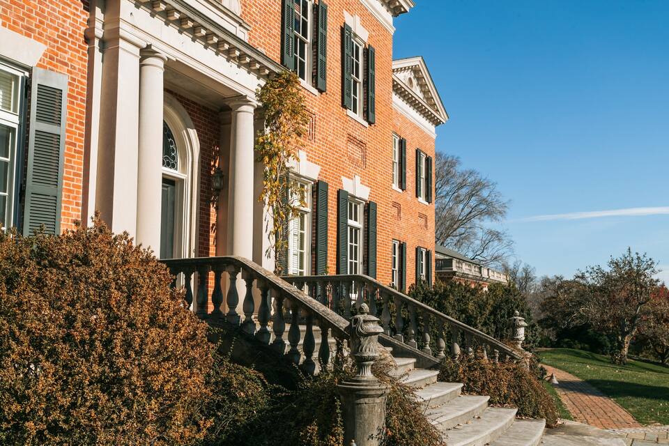 A brick building with a stone staircase and green shutters.