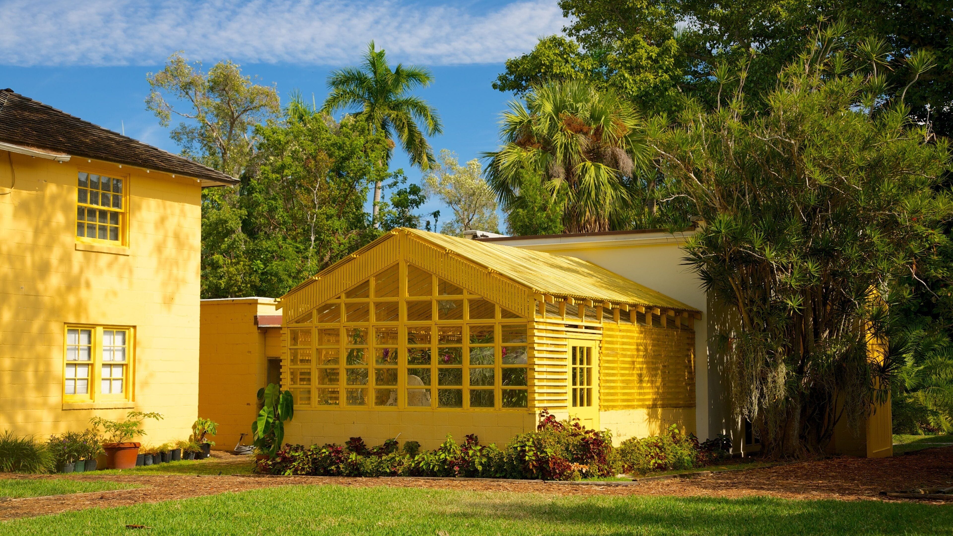 A yellow house with a large window and a porch.