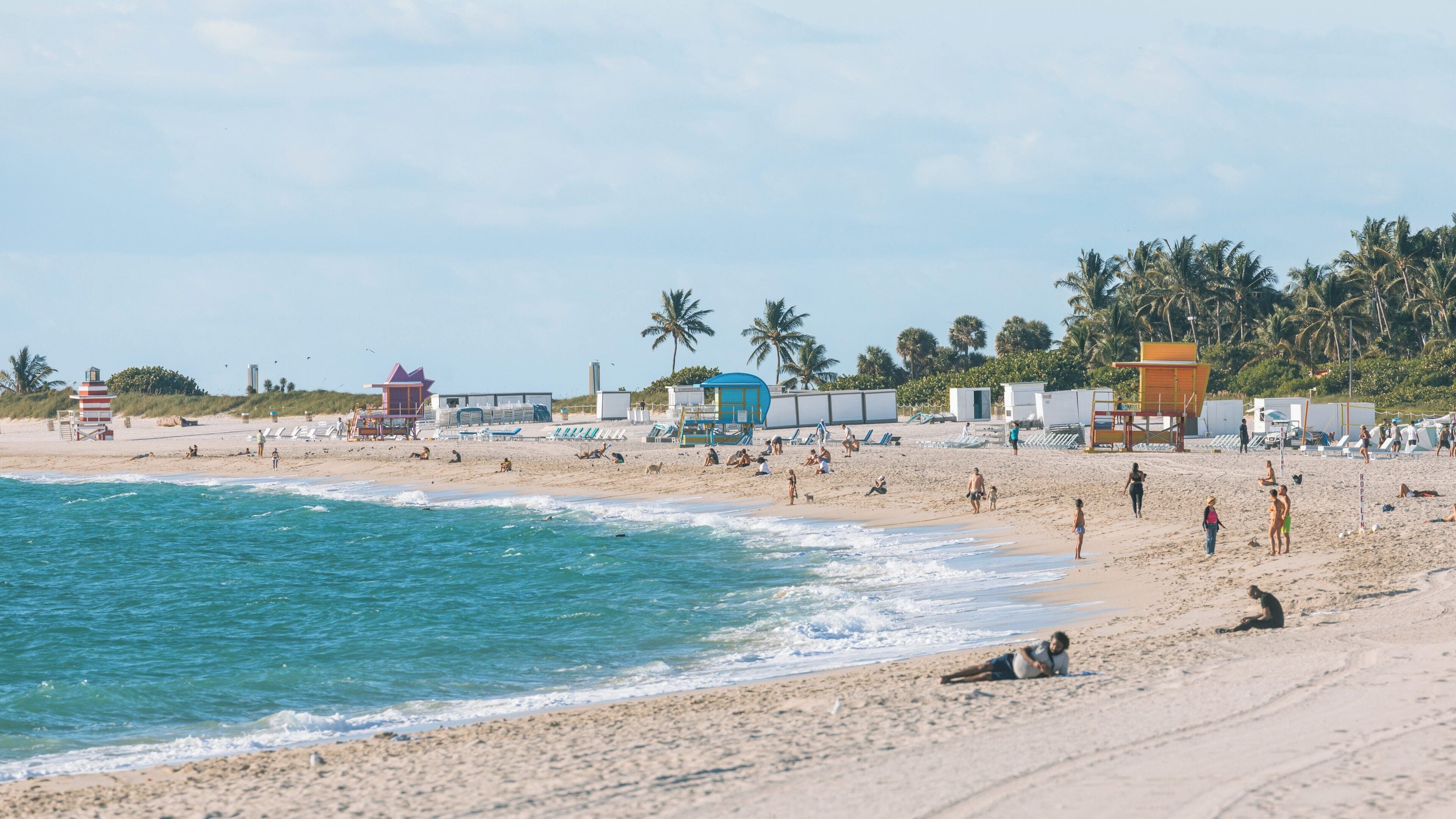 Visitors enjoying the sunny shores of Lummus Park Beach in South Beach, Miami, surrounded by palm trees and coastal vibes on a beautiful day
