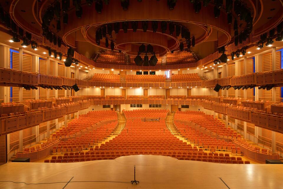 A large, modern auditorium with tiered seating and a central stage.
