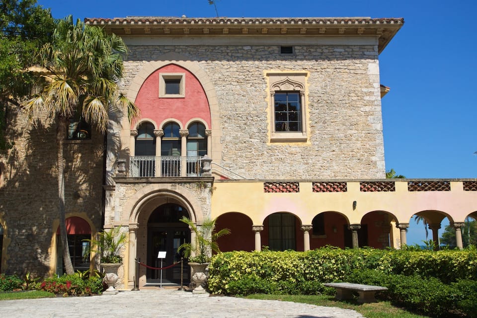 A historic building with a red facade, stone arches, and a balcony.